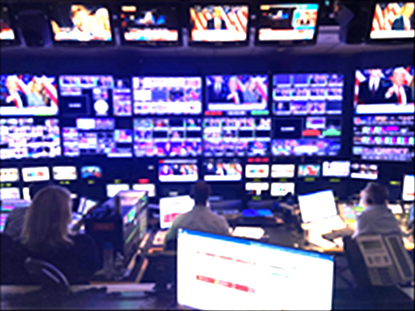 Softly blurred wall of broadcast monitors in a television control room