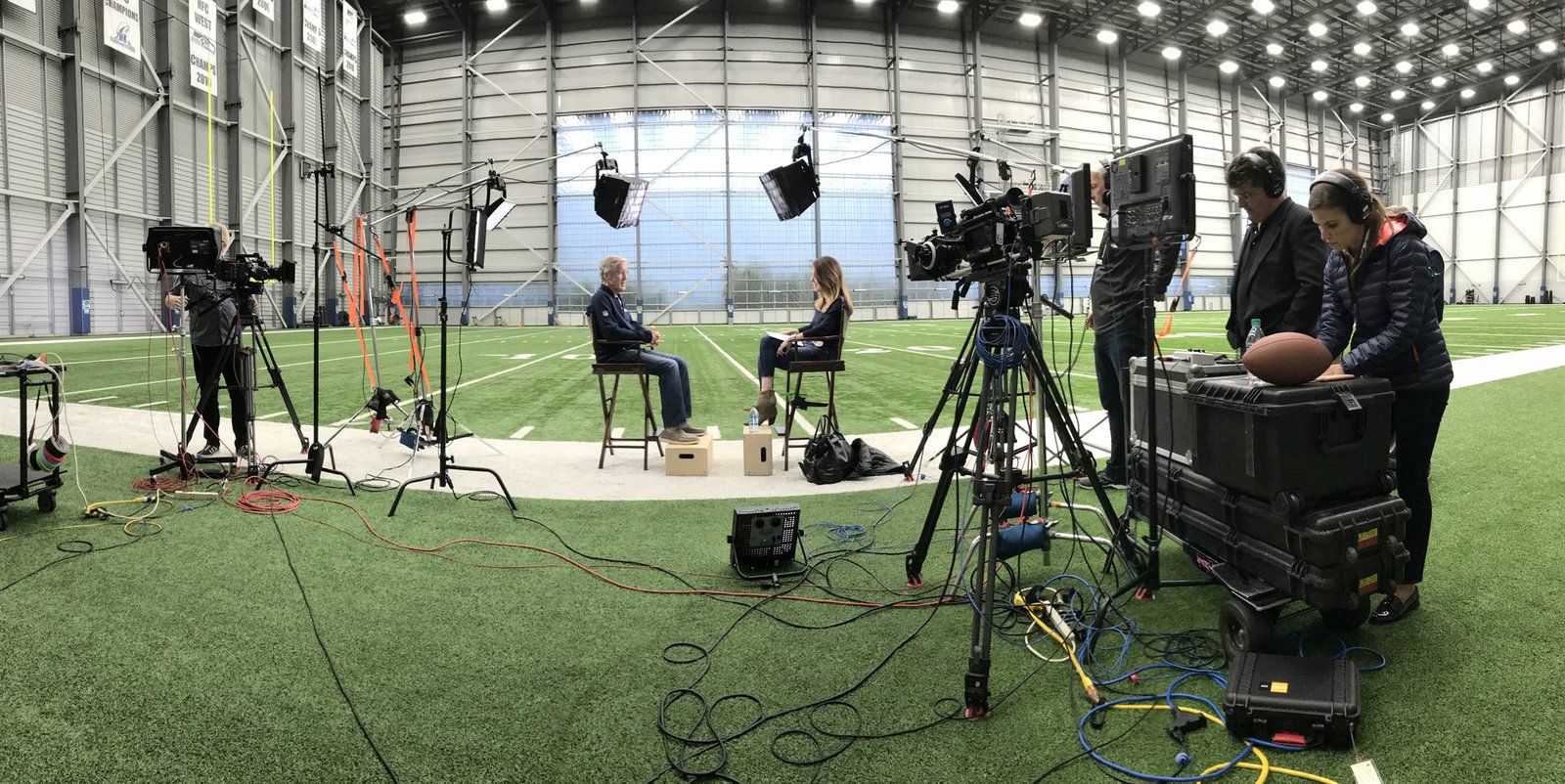 Broadcast interview set with camera operators, lighting and crew preparing for a network shoot
